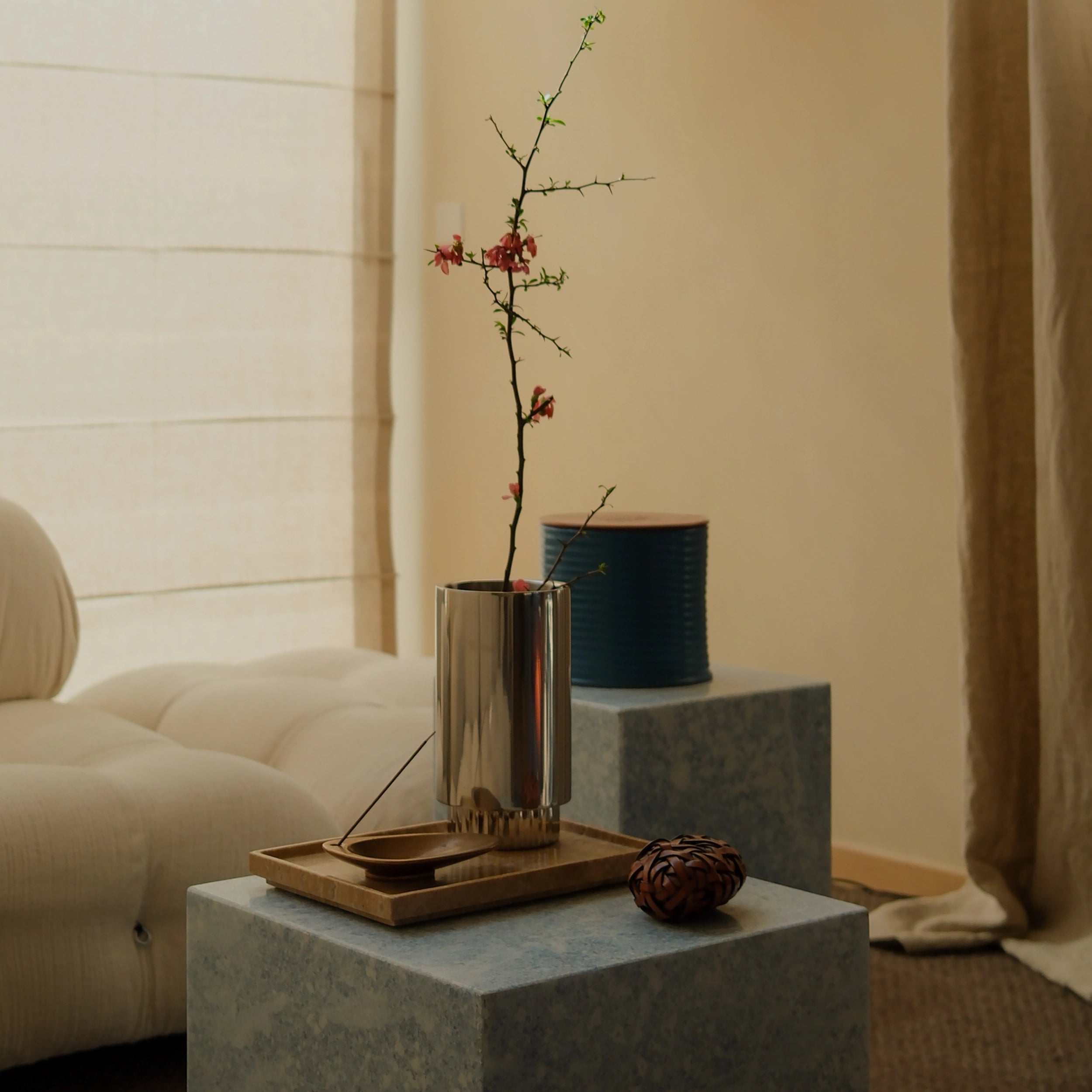 Livingroom Styling with Steel Vase with flower next to a Noce Travertine Tray on a Blue Crystal Marble Side Table