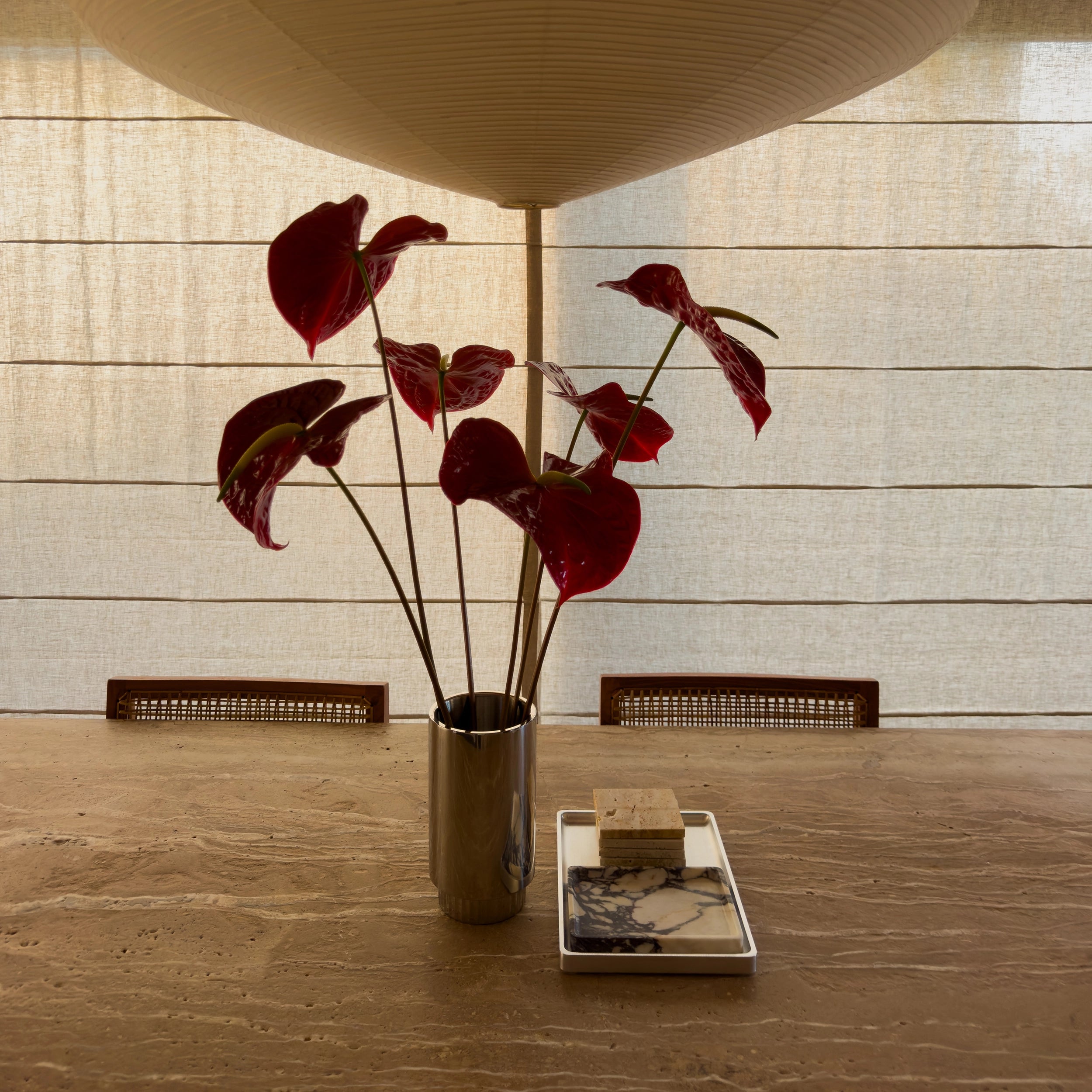 Tablesetting styling Steel vase with red flowers and aluminum tray with travertine coaster and a small Viola Calacatta tray inside