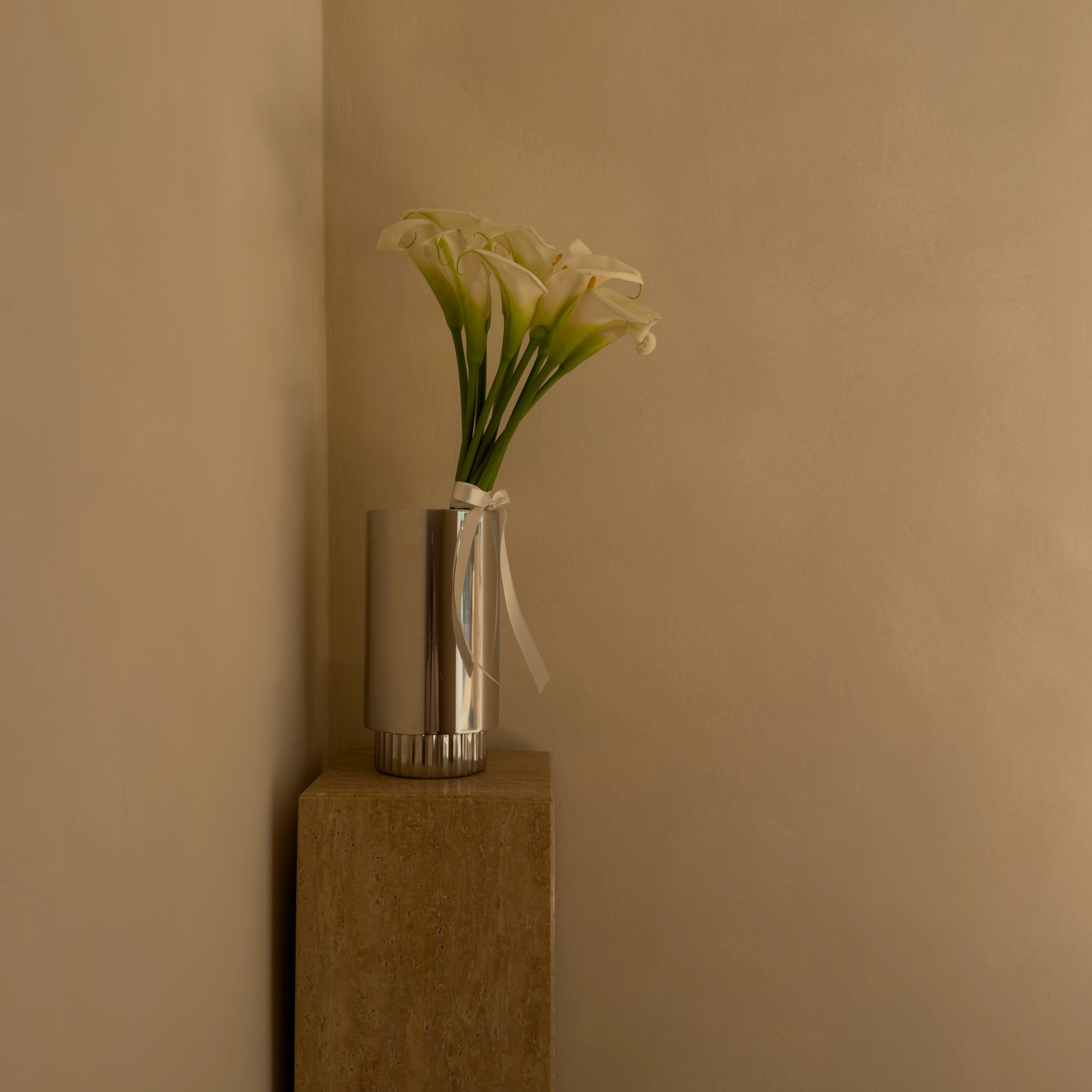 Interior Styling Steel Vase with white flowers on a travertine pedestal